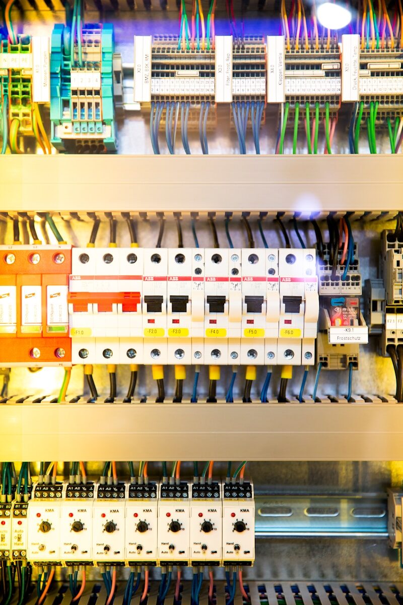 An electrical switch box with circuit breakers and colorful wiring in a control panel